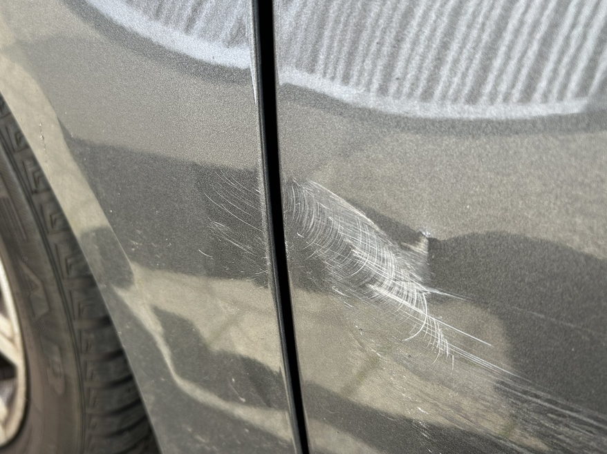 Schadenbild aus einer abgerechneten Akte: Kratzspuren an Tür und Kotflügel eines Kombis, im Streiflicht sichtbar gemacht